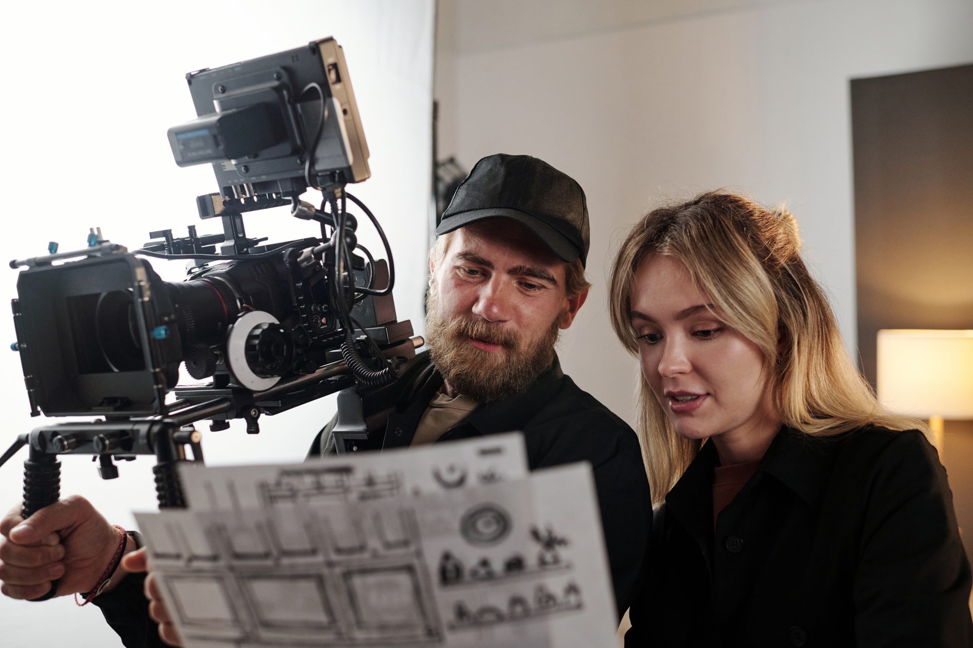 Bearded videographer and his blond female assistant discussing documents