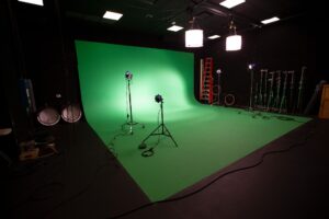 Interior of modern film chroma key studio with green screen and light equipment